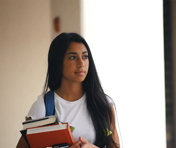 Learning Differences - still of a girl holding books walking through a school hallway - taken from a film produced by Hyperspective